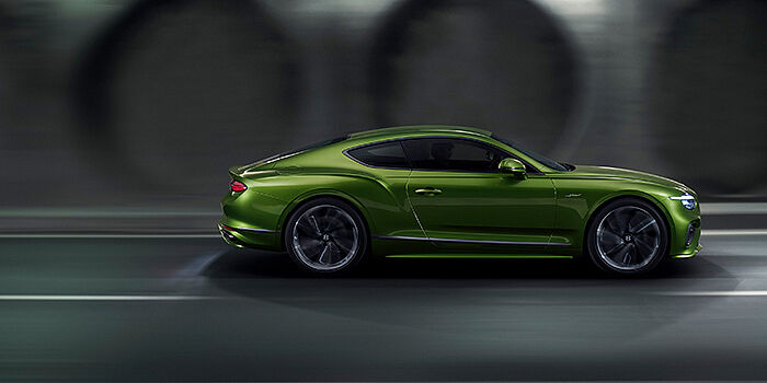 Bentley Taipei Bentley Continental GT coupe in Tourmaline Green paint driving in profile on a dark road
