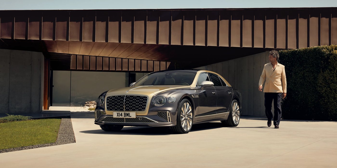 Bentley Taipei Bentley New Flying Spur Mulliner V8 hybrid sedan front three quarters in Rose Gold over Magnetic paint, parked near modern home