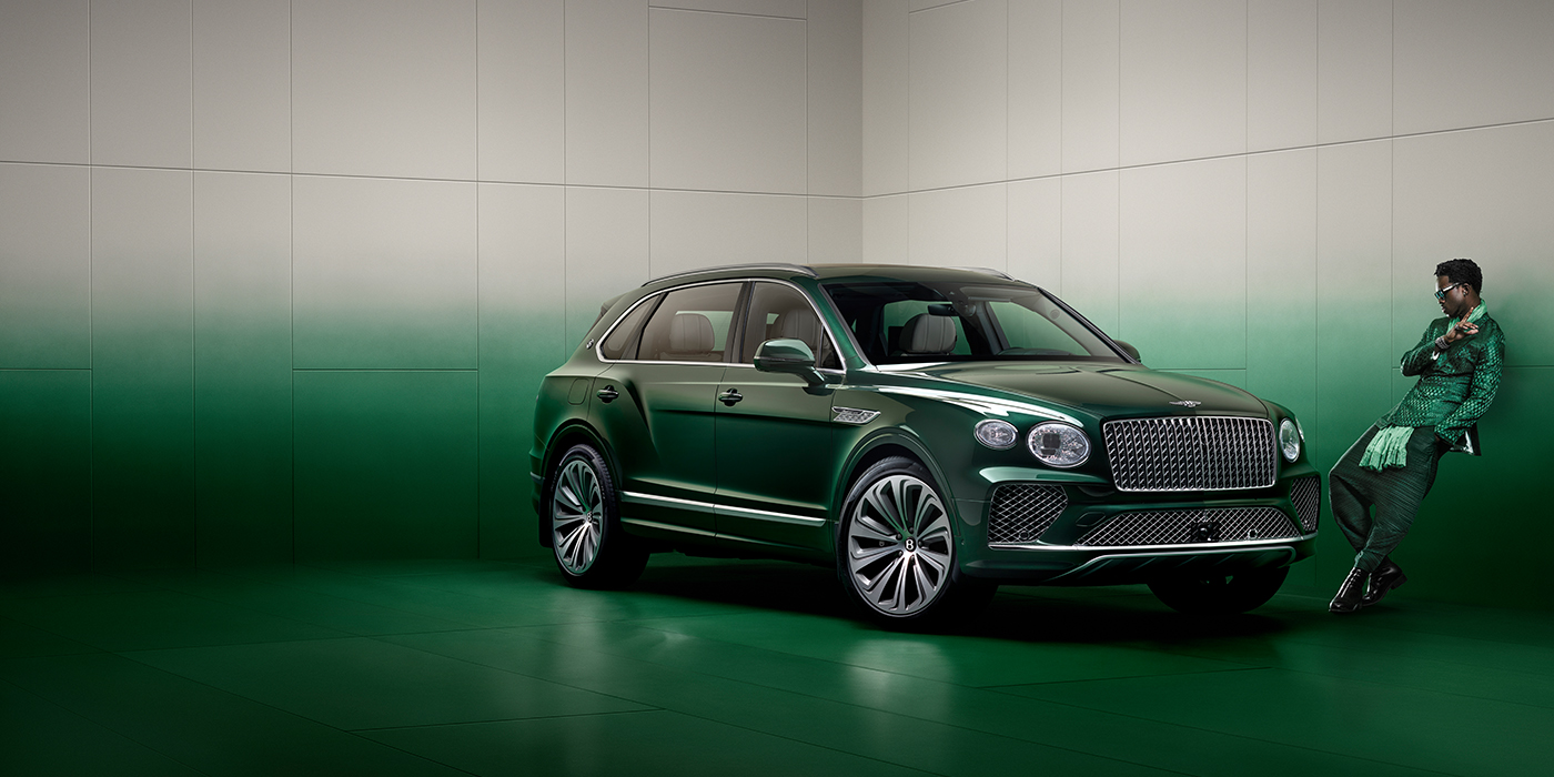Bentley Taipei Wisdom K leans against wall next to Bentley Bentayga Extended Wheelbase Atelier Edition SUV in Light Emerald green paint