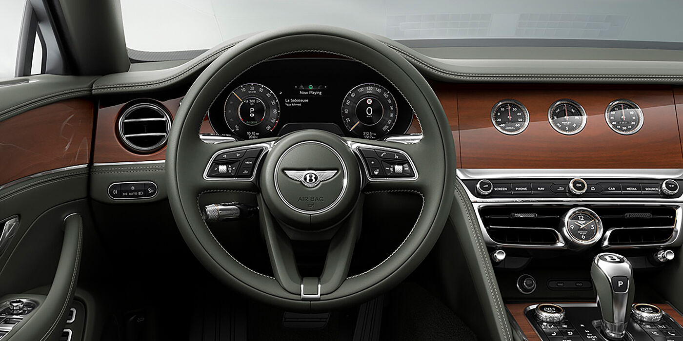 Bentley Taipei New Bentley Flying Spur sedan front cabin in Cumbrian Green hide and Crown Cut walnut veneer showing steering wheel and Rotating Display with three clocks on face