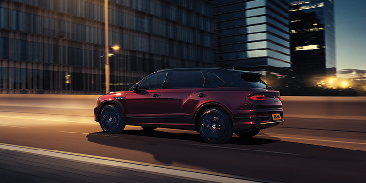 Bentley Taipei Bentley Bentayga Extended Wheelbase Mulliner SUV in Cricket Ball red paint driving dynamically in city at night